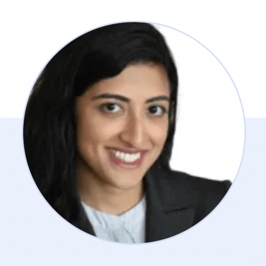 Professional headshot of a woman with long dark hair, wearing a dark blazer and light shirt, smiling at the camera, against a white background.
